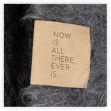 Textile with a quote 'Now is all there ever is.' on a textured background
